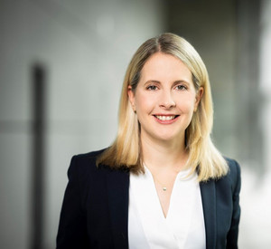 Porträt von Bundesbauministerin Verena Hubertz, die lächelnd in die Kamera blickt. Sie trägt einen dunklen Blazer und eine helle Bluse.